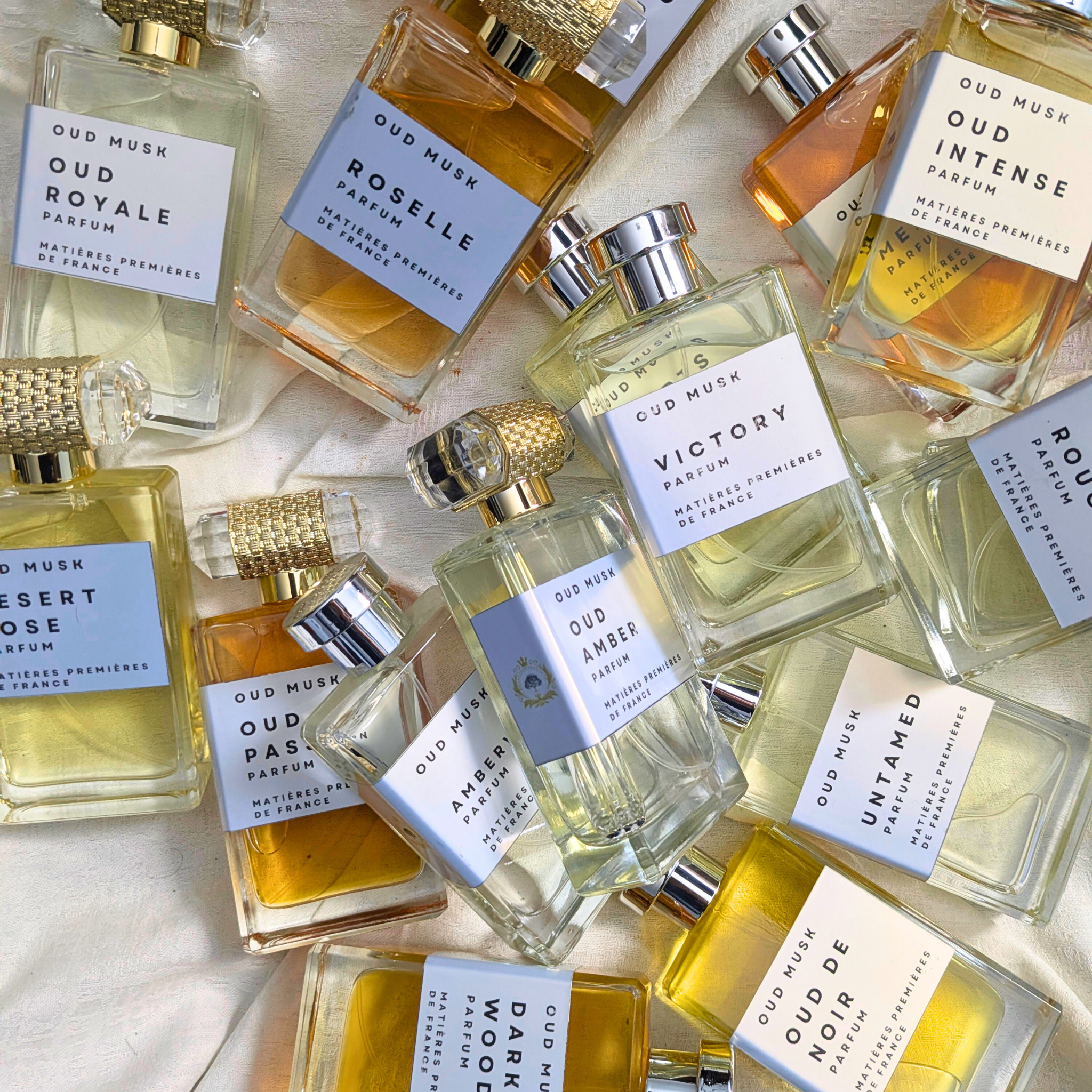Collection of Oud Musk perfume bottles with various labels on a light background